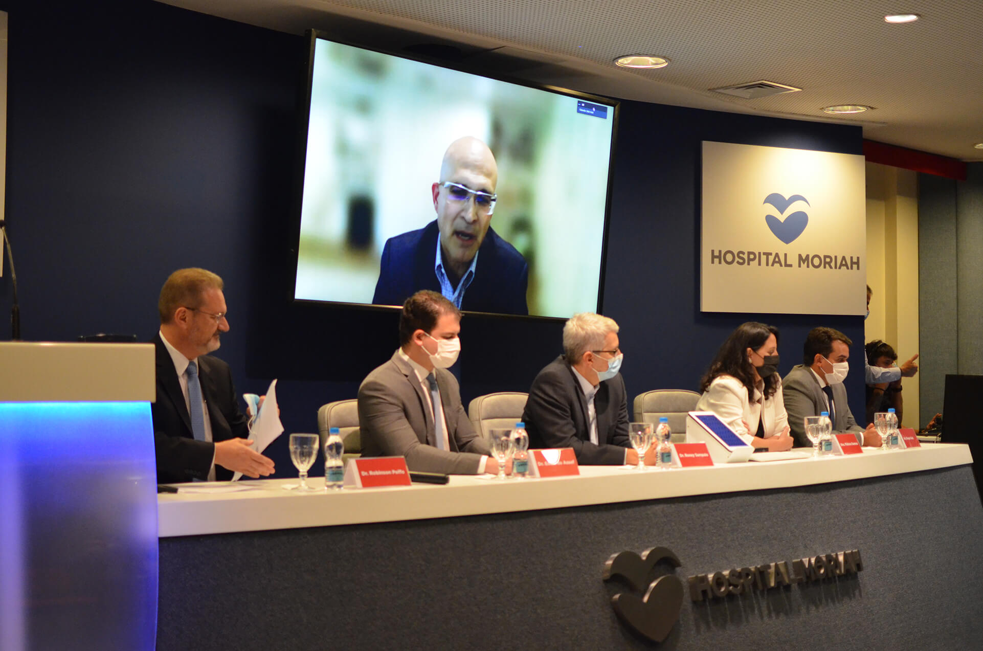 Na mesa, os membros do Instituto de Doenças Valvares: Dr. Robinson Poffo, Dr. Eduardo Assef, Dr. Roney Sampaio, Dra. Fátima Dumas Cintra e Dr. Diego Gaia. Na tela, o Prof. Bob Kiaii, presidente da Associação Internacional de Cirurgia Cardiotorácica Minimamente Invasiva e professor da UC Davis Heart Center